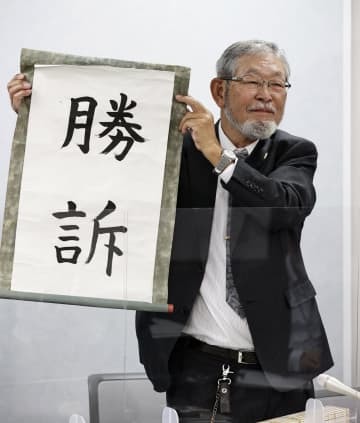 「勝訴」と書かれた垂れ幕を掲げる大阪府泉佐野市側代理人の阿部泰隆弁護士＝10日午後、大阪市
