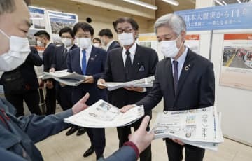 震災写真展で新聞を配る（右から）福島民報社の芳見弘一社長、岩手日報社の東根千万億社長、東京新聞の菅沼堅吾代表＝11日午前、東京都品川区