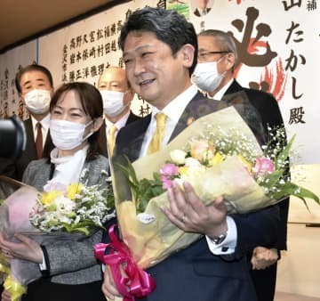 金沢市長選で初当選し、花束を手に笑顔を見せる村山卓氏（手前右）＝13日夜