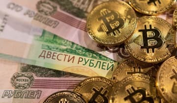 ロシアのルーブル紙幣と、暗号資産（仮想通貨）ビットコインのイメージ写真（ロイター＝共同）