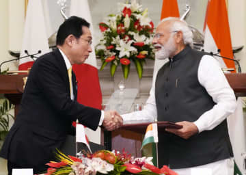 文書を交換しインドのモディ首相（右）と握手する岸田首相＝19日、ニューデリー（共同）