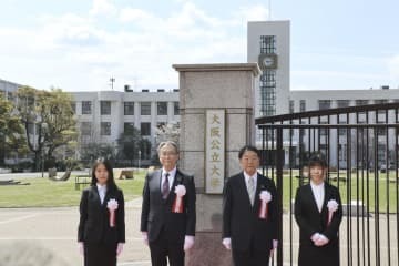 大阪公立大の看板の前で記念写真に納まる辰巳砂昌弘学長（左から2人目）ら＝1日午前、大阪市住吉区