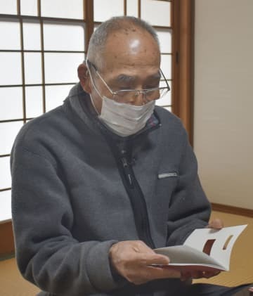 被爆者健康手帳を見る斉藤修吾さん＝1日午後、広島市