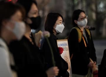 JR東京駅前で行われた「フラワーデモ」。参加者は花やプラカードを手に性暴力撲滅を訴える言葉に耳を傾けた＝11日夜
