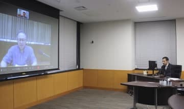 オンラインで沖縄県の玉城デニー知事（画面）と意見交換する山際経済再生相＝14日午後、内閣府
