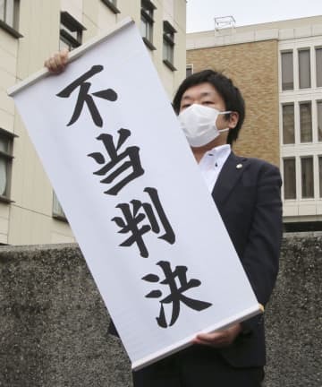 判決後、「不当判決」と書かれた幕を掲げる弁護士＝20日午前、さいたま地裁前