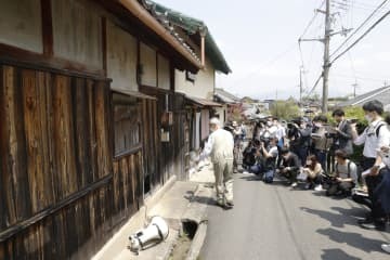 滋賀県日野町の強盗殺人事件で、殺害現場とされる酒店だった建物の前で説明を受ける報道関係者ら＝23日午後