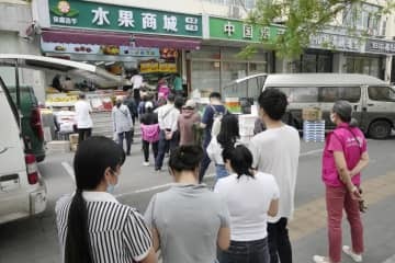 果物や野菜を売る商店に並ぶ市民ら＝25日、北京市朝陽区（共同）