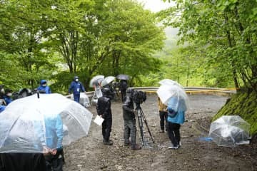 規制線が張られた現場周辺に集まる報道陣＝29日午後、山梨県道志村