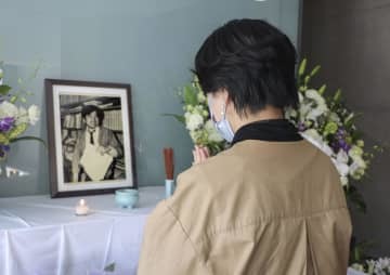 小尻知博記者の遺影に手を合わせる女性＝3日、兵庫県西宮市の朝日新聞阪神支局