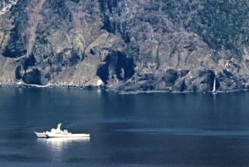 北海道・知床半島沖で捜索する海上保安庁の巡視船。右奥はカシュニの滝＝6日午後1時54分（共同通信社ヘリから）