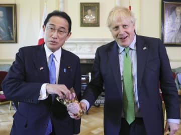 5日、福島産のポップコーンを手にするジョンソン英首相（右）と岸田首相＝ロンドン（英首相官邸提供・共同）