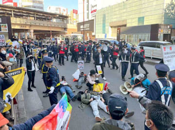 市民団体のデモを妨害しようとJR吉祥寺駅前の車道に寝そべる人たち＝2021年12月4日、東京都武蔵野市