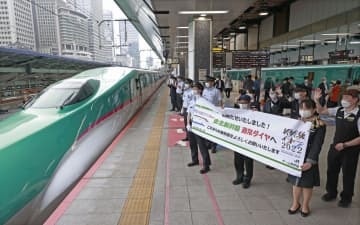 東北新幹線が完全復旧して通常ダイヤとなり、車両に向かって横断幕を掲げるJR東日本の社員ら＝13日午前、JR東京駅