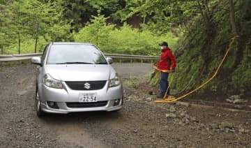 山梨県道志村の山中で、規制線の外に出る車両＝17日午後