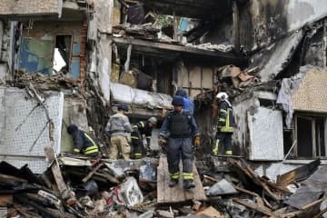 ロシア軍の攻撃で破壊された集合住宅での救助活動＝18日、ウクライナ・ドネツク州（AP＝共同）
