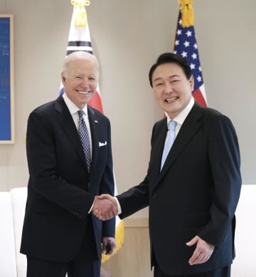 21日、ソウルで初会談し、握手するバイデン米大統領（左）と韓国の尹錫悦大統領（大統領府提供・共同）