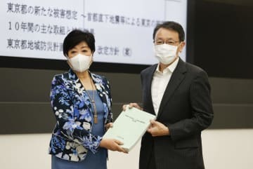 東京都の防災会議で、地震部会長の平田直東京大名誉教授（右）から報告書を受け取る小池百合子知事＝25日午前、東京都庁