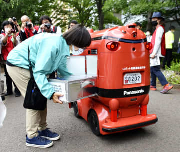 商品を積み込まれる自動配送ロボット＝26日、茨城県つくば市