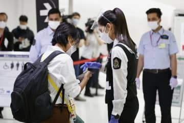 成田空港に到着し、空港職員（手前右）に携帯電話の専用アプリ画面を見せる人＝1日