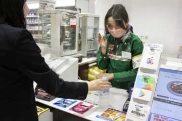 日本生命保険が社内に開業した売店で、指さし確認や手話で対応する職員（右）＝5月、大阪市