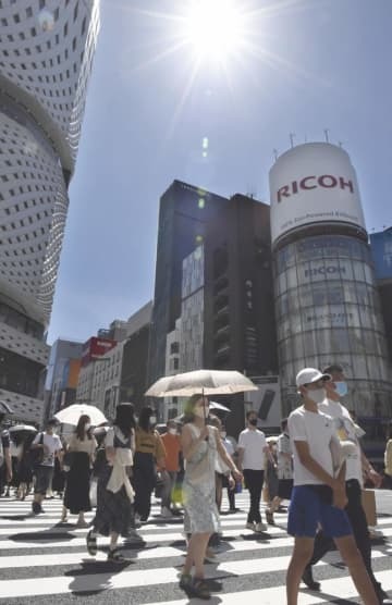強い日差しが照りつける中、東京・銀座を歩く買い物客ら＝21年7月