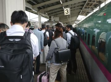 東北新幹線（右）が停車し、白石蔵王駅で後続の列車に乗り換える人たち＝23日午前11時51分、宮城県白石市