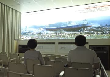 閉館の日を迎えた津波体験館で映像を見る来館者＝26日午後、宮城県気仙沼市