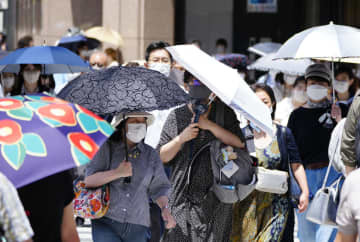 猛烈な暑さの中、日傘を差して歩く人たち＝26日午後、東京・銀座