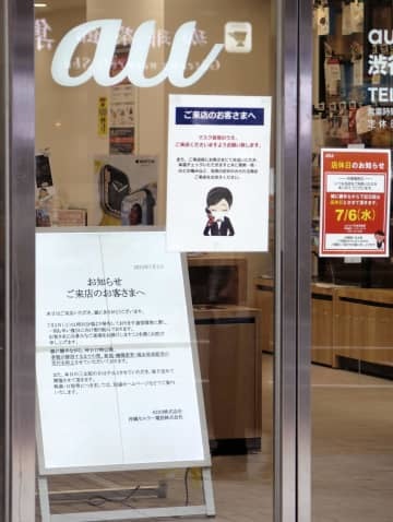 KDDI（au）の大規模通信障害について謝罪の看板を掲げるJR渋谷駅近くのauショップ＝3日午後、東京都渋谷区