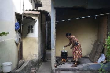 まきを燃やして料理する女性＝6月23日、スリランカ・コロンボ（AP＝共同）