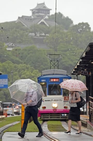 傘を差して熊本市内を歩く人たち。上は熊本城＝5日午前8時11分