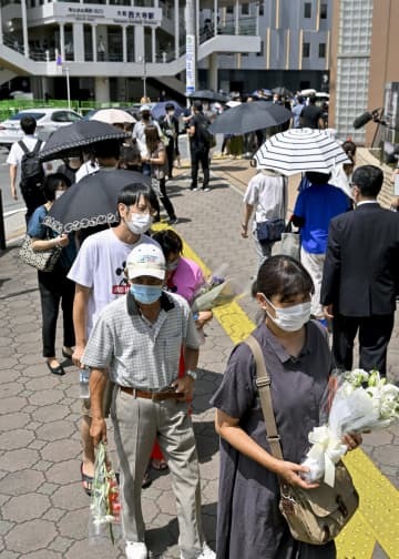 安倍元首相が銃撃された現場付近に設置された献花台に並ぶ人たち＝9日午前10時36分、奈良市