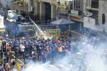 9日、スリランカ・コロンボで、放水砲や催涙ガスを使いデモ隊の鎮圧に当たる警察（AP＝共同）