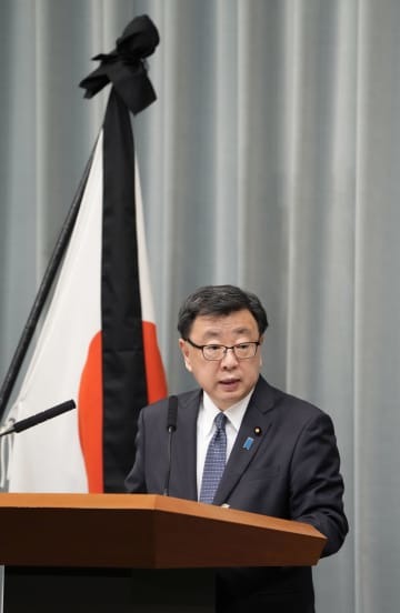 弔旗の前で記者会見する松野官房長官＝11日午前、首相官邸
