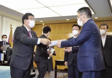 KDDIの高橋誠社長（手前右）に行政指導の文書を渡す金子総務相＝3日午後、総務省