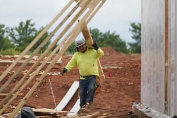 住宅建設現場で板を運ぶ作業員＝2021年6月、米オクラホマ州（AP＝共同）