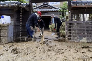 ボランティアと泥をかき出す男性（左）＝8日、福井県南越前町