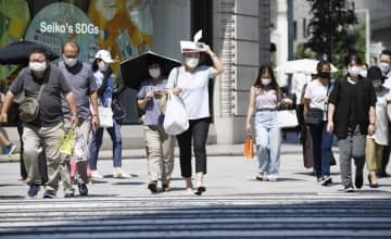 強い日差しの中、マスク姿で横断歩道を渡る人たち＝9日午後、東京都中央区