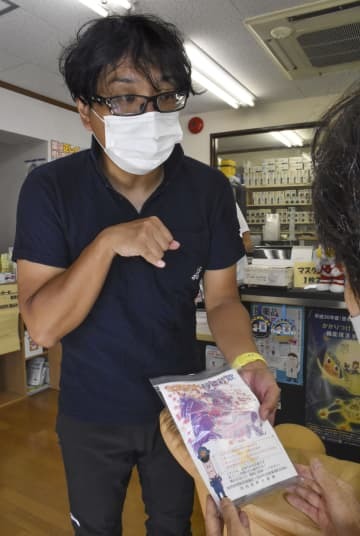 薬局で特殊詐欺の啓発チラシを入れた薬袋を手渡す船多大さん＝22日午前、大阪府河内長野市