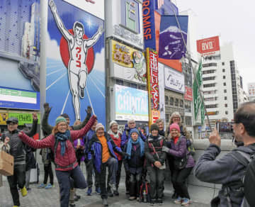 大阪・ミナミの名所、グリコの看板前でポーズを取る訪日観光客ら＝2019年4月