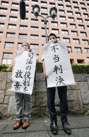 控訴審判決後に「不当判決」と書かれた紙を掲げる矢崎暁子弁護士（左）と堀江哲史弁護士＝26日午前、名古屋高裁前