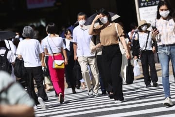 強い日差しの中、大阪・梅田を歩く人たち＝6月28日