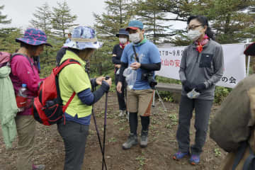 浅間山の黒斑コース登山口で、登山者（左側）に安全な登山を呼びかける「山びこの会」のメンバーら＝4日午前