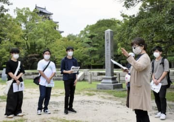 旧陸軍第5師団の旧庁舎跡で学芸員（右手前）の説明を聞く広島経済大の学生ら＝10日午前、広島市