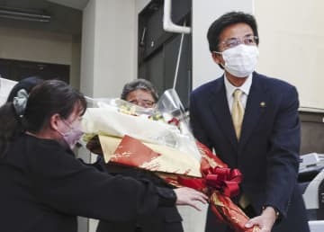 当選が決まり、事務所で花束を受け取る斉藤栄氏（右）＝11日夜、静岡県熱海市