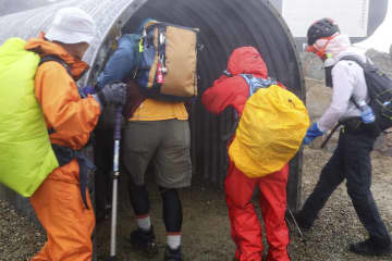 御嶽山の噴火災害を想定した避難訓練で、山頂の剣ケ峰付近のシェルターに逃げ込む参加者＝17日午後