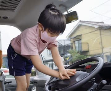 通園バスの運転席に乗りクラクションを鳴らす年長園児＝20日午前、富山市