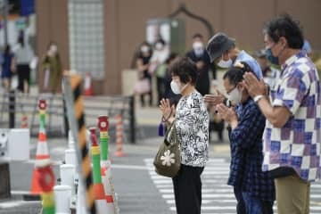 安倍元首相銃撃事件の現場付近で手を合わせる人たち＝27日午後1時21分、奈良市