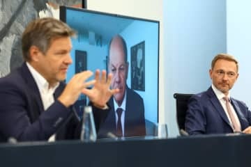 29日、エネルギー価格高騰対策などについてオンラインで記者会見するドイツのショルツ首相（中央）ら（ロイター＝共同）